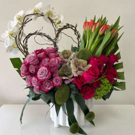 Pink roses and white orchids in a white vase with tulips