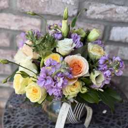Bouquet of peach, white, and yellow roses with purple flowers