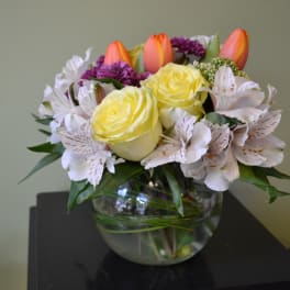 Yellow roses and white alstroemeria in a glass bowl vase