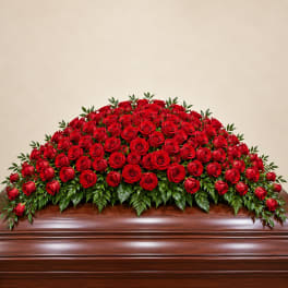 Large red rose casket spray on a wooden casket
