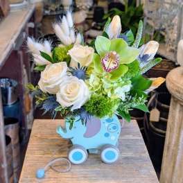 White roses and green orchids in a blue elephant planter