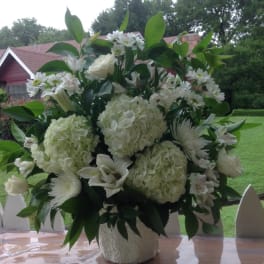 White floral arrangement in a textured vase with hydrangeas and daisies