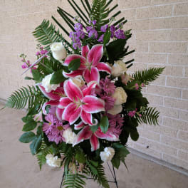 Standing spray with pink lilies, white roses, and purple flowers