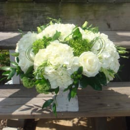 White floral arrangement in a stone vase with roses and hydrangeas