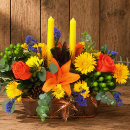 Orange and yellow floral centerpiece with two yellow candles