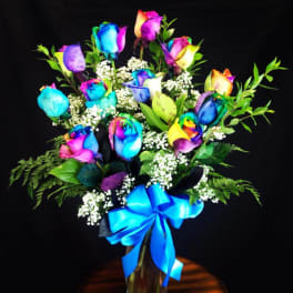 Bouquet of rainbow-colored roses with baby's breath and a blue ribbon in a vase