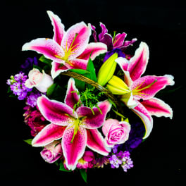 Pink stargazer lilies and roses in a basket arrangement