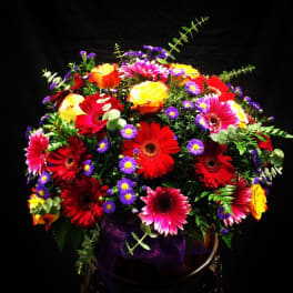 Bright mixed bouquet of gerbera daisies and roses with purple filler flowers