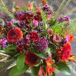 Mixed bouquet with red, orange, and purple flowers in a vase