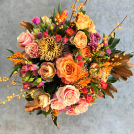 Mixed bouquet of peach and pink roses with orange accents