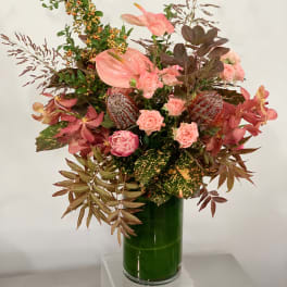 Pink floral arrangement in a tall green glass vase