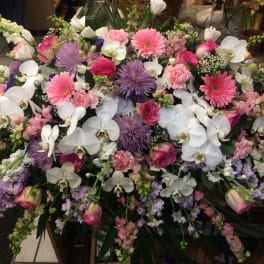 Large mixed floral arrangement with white orchids, pink gerberas, and purple blooms
