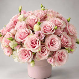 Pink roses and small white flowers arranged in a pink vase