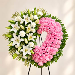 Heart-shaped floral wreath with pink roses and white lilies on a stand