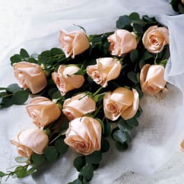 Peach roses arranged with eucalyptus on white fabric