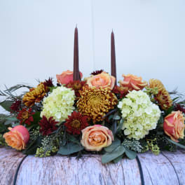 Low floral centerpiece with peach roses, white hydrangeas, and burgundy candles