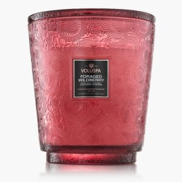 Red patterned glass candle jar with a black label