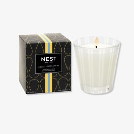 Boxed scented candle beside a lit glass candle