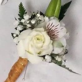 White floral boutonniere with a green bud and small white accents