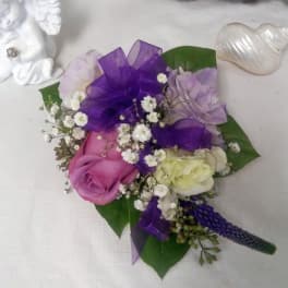 Small bouquet of purple and pink roses with white filler flowers and ribbon