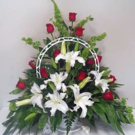 White lilies and red roses arranged in a white basket