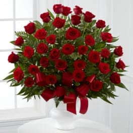Bouquet of red roses in a white vase with a red ribbon