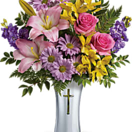 Mixed bouquet of pink lilies, roses, and purple flowers in a clear vase