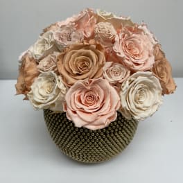 Bouquet of pale peach and ivory roses in a textured gold vase