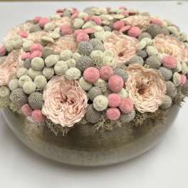 Round floral arrangement in a low metallic bowl with blush and pink blooms