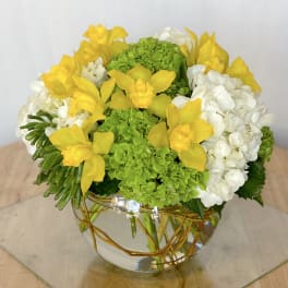Yellow orchids and white hydrangeas in a glass bowl vase