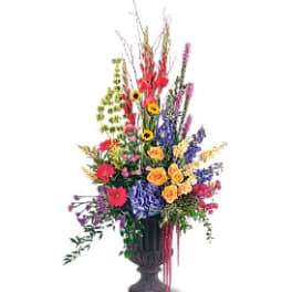 Tall mixed flower arrangement in a dark urn vase