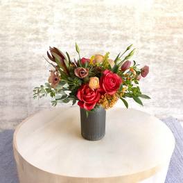 Bouquet of red and peach flowers in a ribbed vase