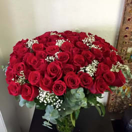 Large bouquet of red roses in a glass vase with white filler flowers
