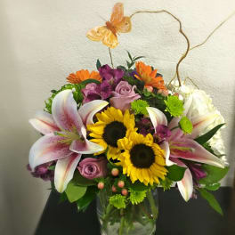 Mixed bouquet in a glass vase with sunflowers, lilies, and roses