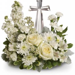 White floral arrangement with a silver cross centerpiece