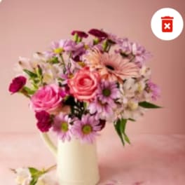 Mixed pink and purple flowers in a white pitcher vase