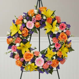 Colorful floral wreath on a black easel with orange, yellow, pink, and purple blooms