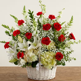 Basket arrangement of red roses, white lilies, and white snapdragons