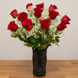 Red roses in a black vase with white filler flowers
