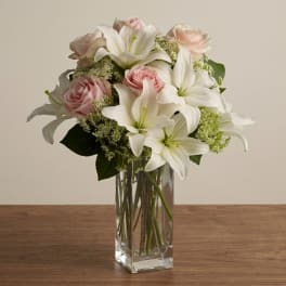 Pink roses and white lilies arranged in a clear glass vase