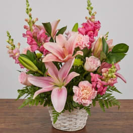 Pink lilies and mixed pink flowers arranged in a white basket