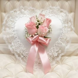Heart-shaped lace pillow with pink roses and a satin ribbon
