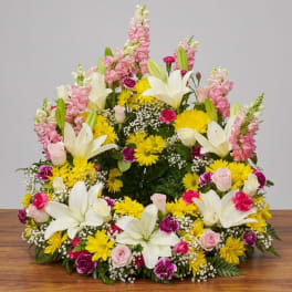 Large floral spray with white lilies, pink snapdragons, and yellow daisies