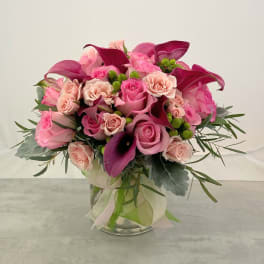 Pink and magenta bouquet with roses and calla lilies in a glass vase