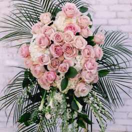 Pink rose standing spray with white flowers and palm fronds
