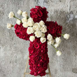 Cross-shaped floral arrangement of red and white roses on a stand