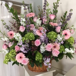 Large basket arrangement of pink roses, gerbera daisies, and purple flowers