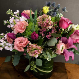 Mixed bouquet of pink, purple, and yellow flowers in a green vase