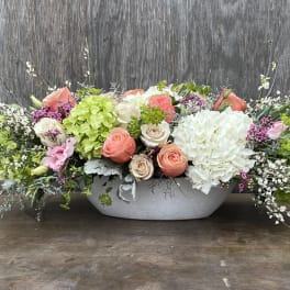 Low floral centerpiece with pink and white roses in a white container