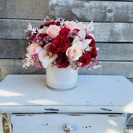 Red and blush roses arranged in a white vase